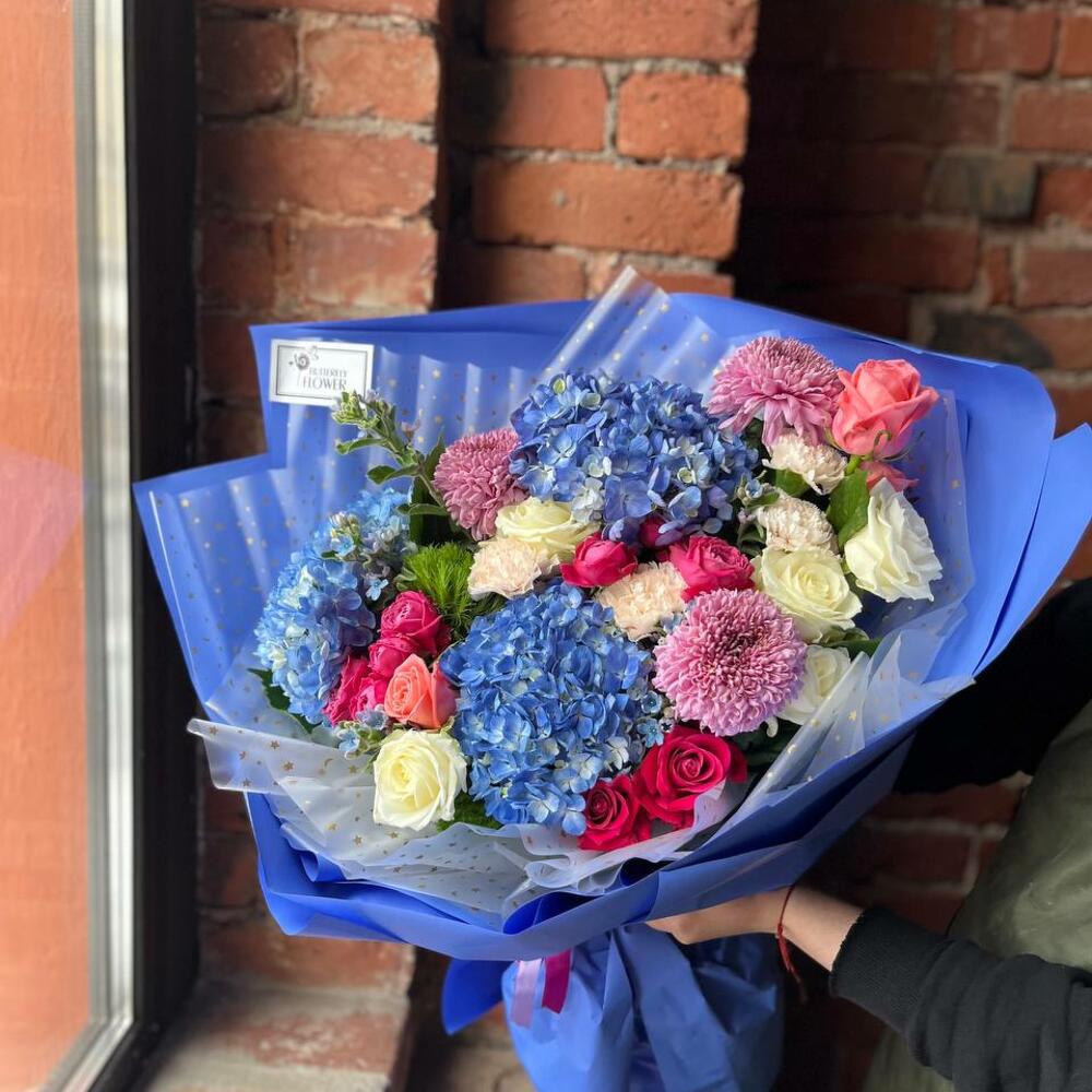 Букет из гортензии, хризантемы, гвоздики, оксипеталума и роз в стильной упаковке